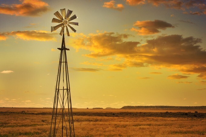 Windmill in African savannah landscape and beautiful sunset